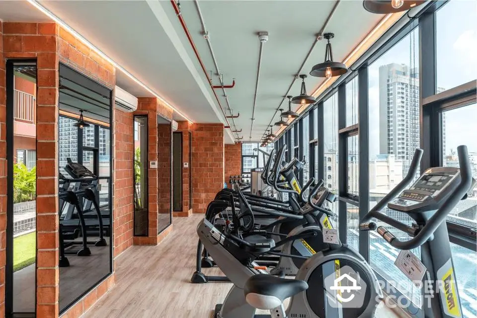 Modern gym with city view and state-of-the-art equipment in luxury apartment building.