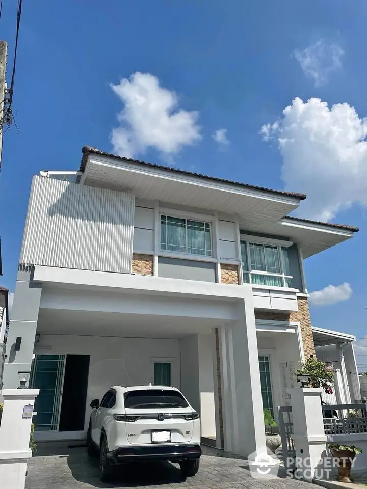 Modern two-story house with carport and white SUV parked, under a clear blue sky.