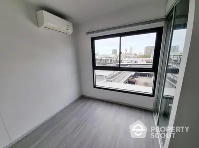 Modern empty room with large window and city view, featuring sleek flooring and air conditioning.