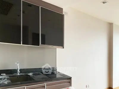 Modern kitchen with sleek black cabinets and induction cooktop in a contemporary apartment.