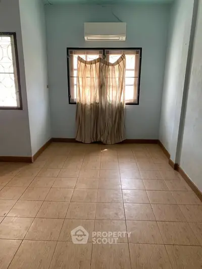 Spacious empty room with tiled floor and air conditioning, ideal for customization.
