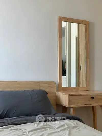 Modern bedroom with wooden furniture and stylish mirror, perfect for cozy living.