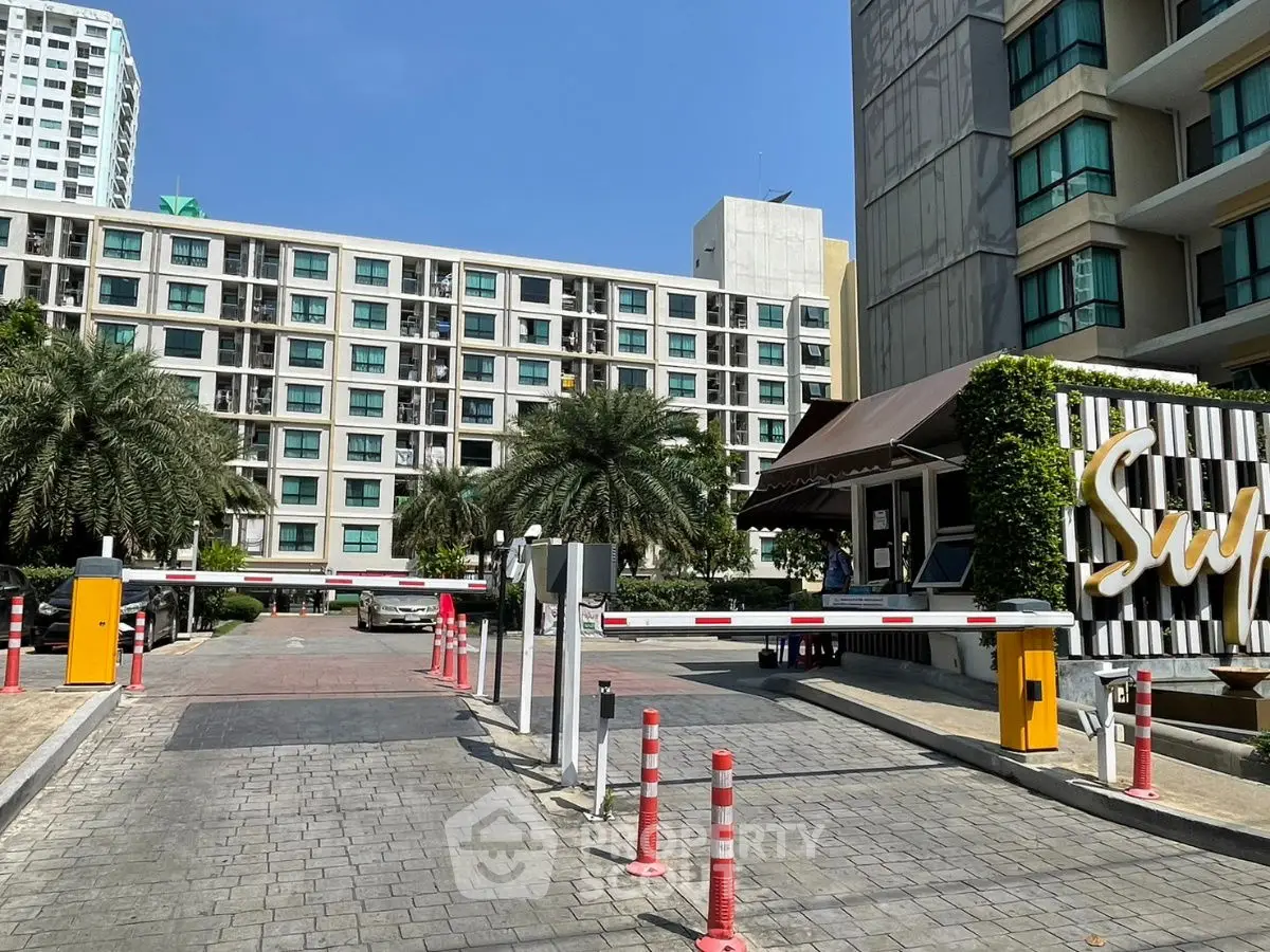 Modern residential building with secure entrance and palm trees in urban setting.