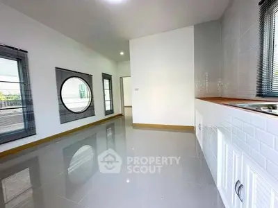 Spacious modern kitchen with sleek white cabinetry and unique circular window design.