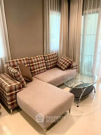 Stylish living room with modern plaid sofa and glass coffee table, perfect for cozy gatherings.