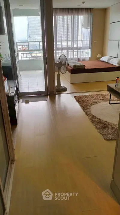 Spacious modern studio with balcony and city view, featuring sleek wooden flooring and cozy sleeping area.