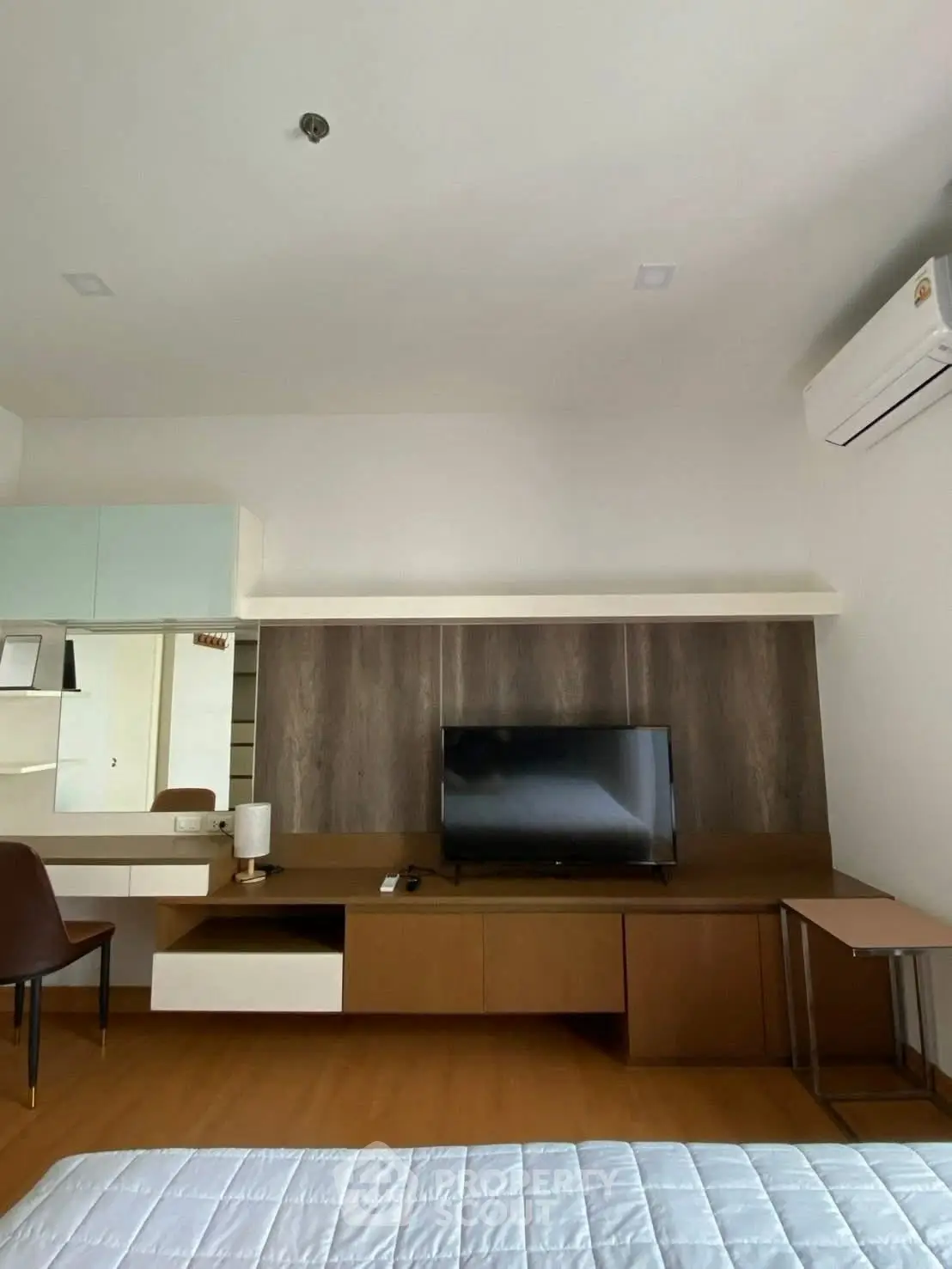 Modern bedroom with TV, air conditioning, and stylish wooden furniture.