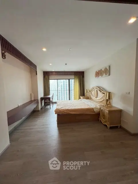 Spacious bedroom with elegant decor and city view, featuring wooden flooring and ample natural light.