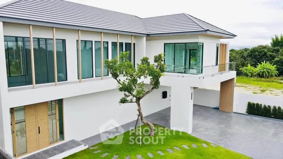 Modern two-story house with large windows and lush green lawn