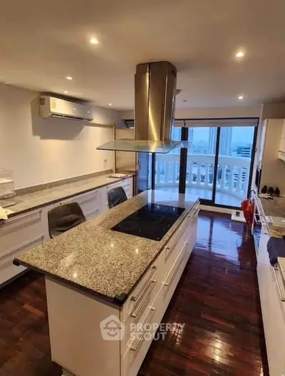 Spacious modern kitchen with granite countertops and open layout, featuring city view from balcony.