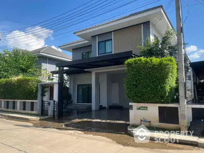 Modern two-story house with lush greenery and spacious driveway in suburban neighborhood.