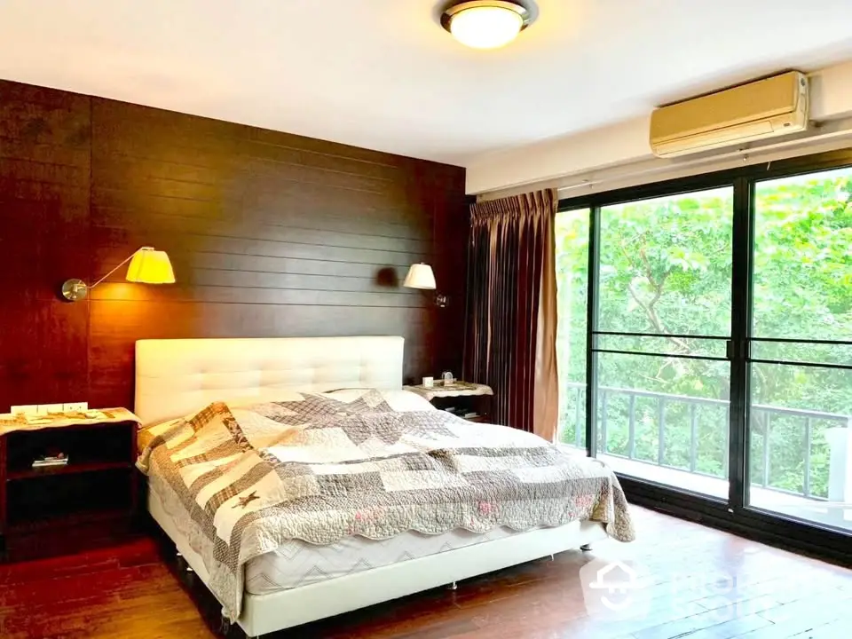 Spacious bedroom with large window and lush greenery view