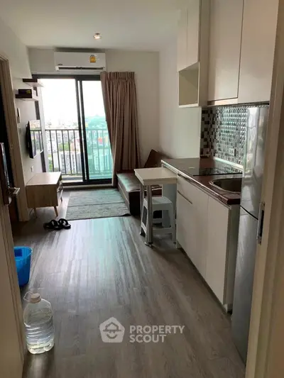Modern studio apartment with balcony and compact kitchen in urban setting