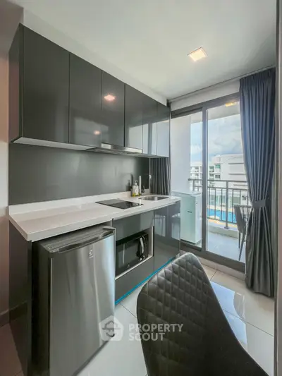 Modern kitchen with sleek cabinets and balcony view in luxury apartment.