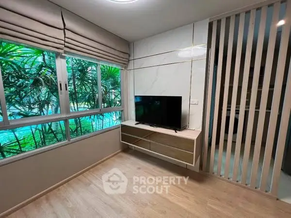 Modern living room with large window and sleek TV setup, featuring stylish wooden flooring.