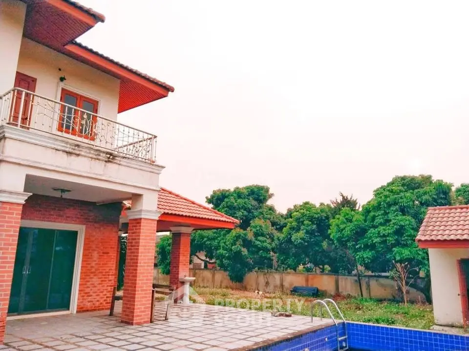 Charming two-story home with spacious balcony and inviting pool, surrounded by lush greenery for serene living.