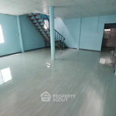 Spacious open-plan interior with modern staircase and glossy flooring, ideal for versatile living or office space.