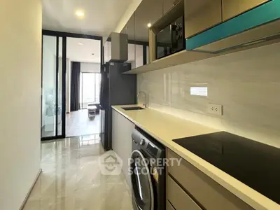 Modern kitchen with sleek appliances and washing machine in stylish apartment.