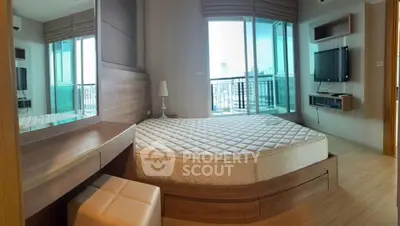 Spacious bedroom with modern decor and city view balcony access.