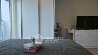 Modern bedroom with cozy decor and natural light, featuring a sleek TV and stylish furniture.