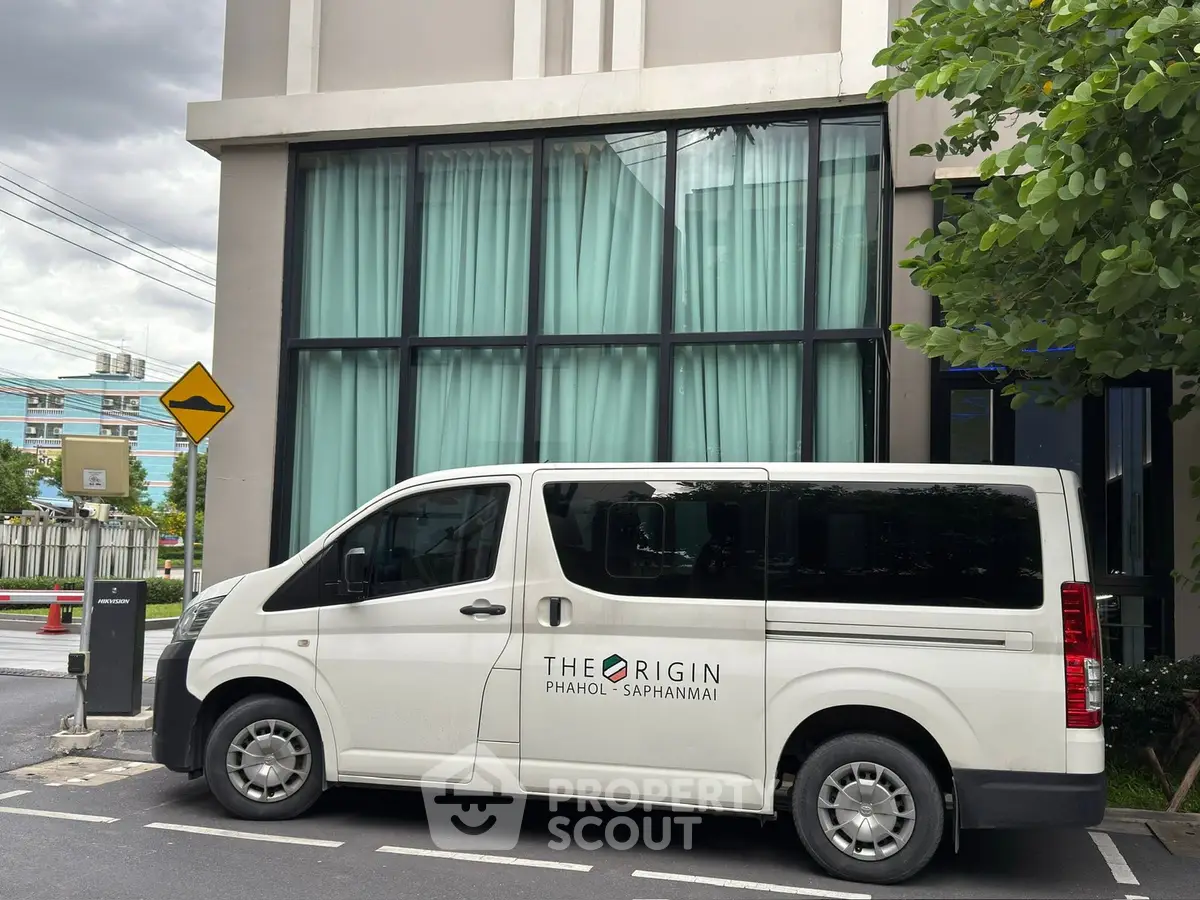 Modern building exterior with large windows and a branded van parked outside, showcasing urban living.