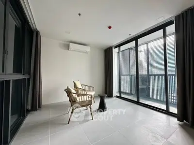Spacious modern balcony with stylish seating and large glass doors in a contemporary apartment.
