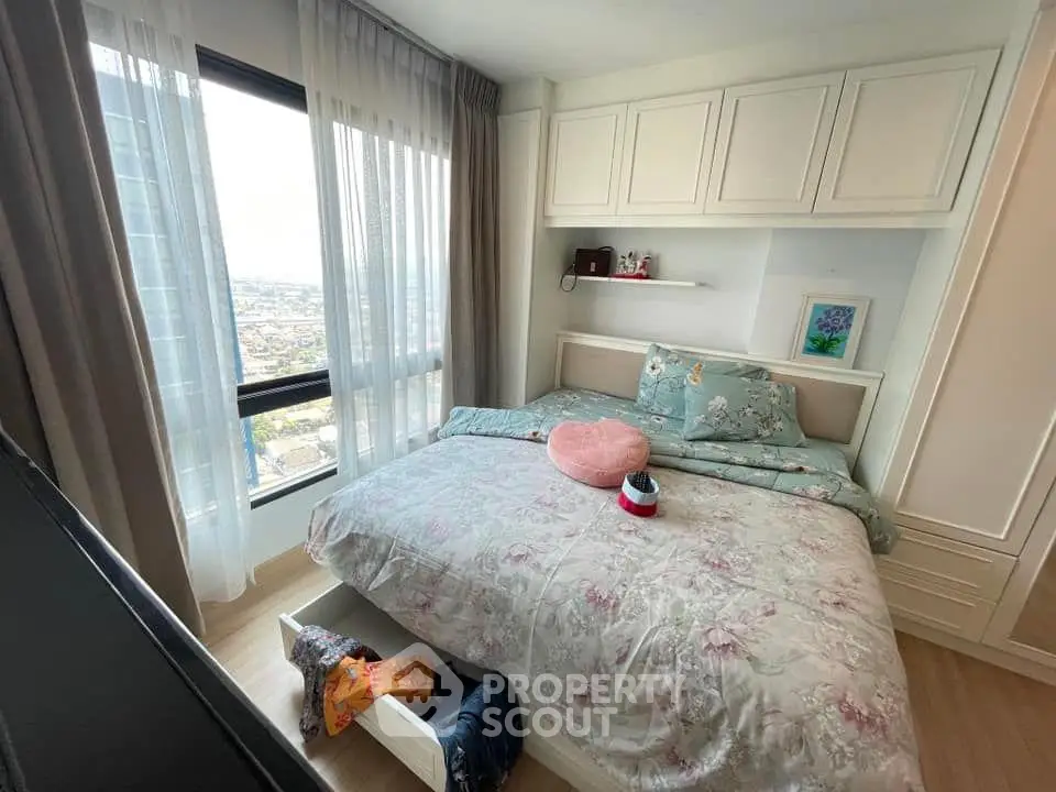 Cozy bedroom with large window offering stunning city view, featuring elegant decor and ample storage space.