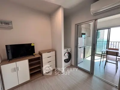 Modern apartment interior with balcony view, featuring a compact living area and kitchen appliances.