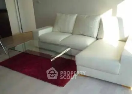 Modern living room with white sectional sofa and glass coffee table on red rug