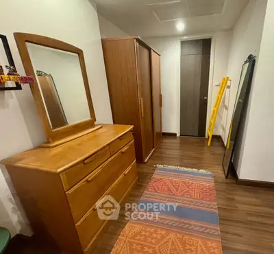 Spacious bedroom with wooden furniture and colorful rug, perfect for cozy living.