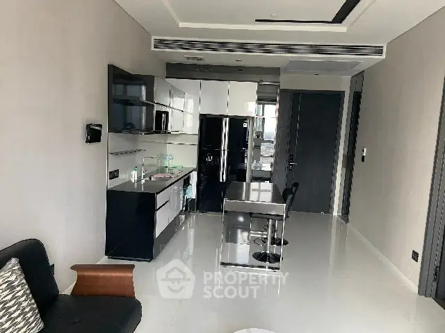 Modern kitchen with sleek black cabinetry and dining area in contemporary apartment.
