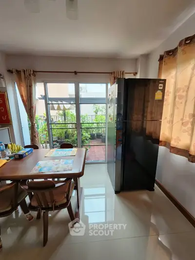 Bright kitchen with dining area and balcony view, featuring modern appliances and natural light.