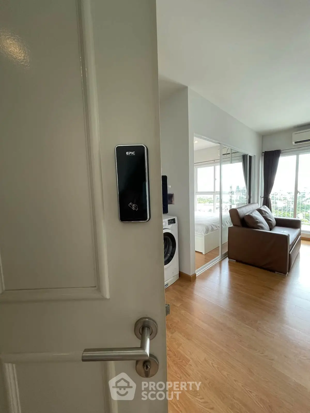Modern apartment interior with smart lock, washing machine, and cozy living area with large windows.