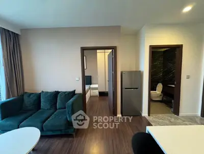 Modern apartment interior with cozy living room and visible bathroom, featuring stylish furniture and sleek flooring.