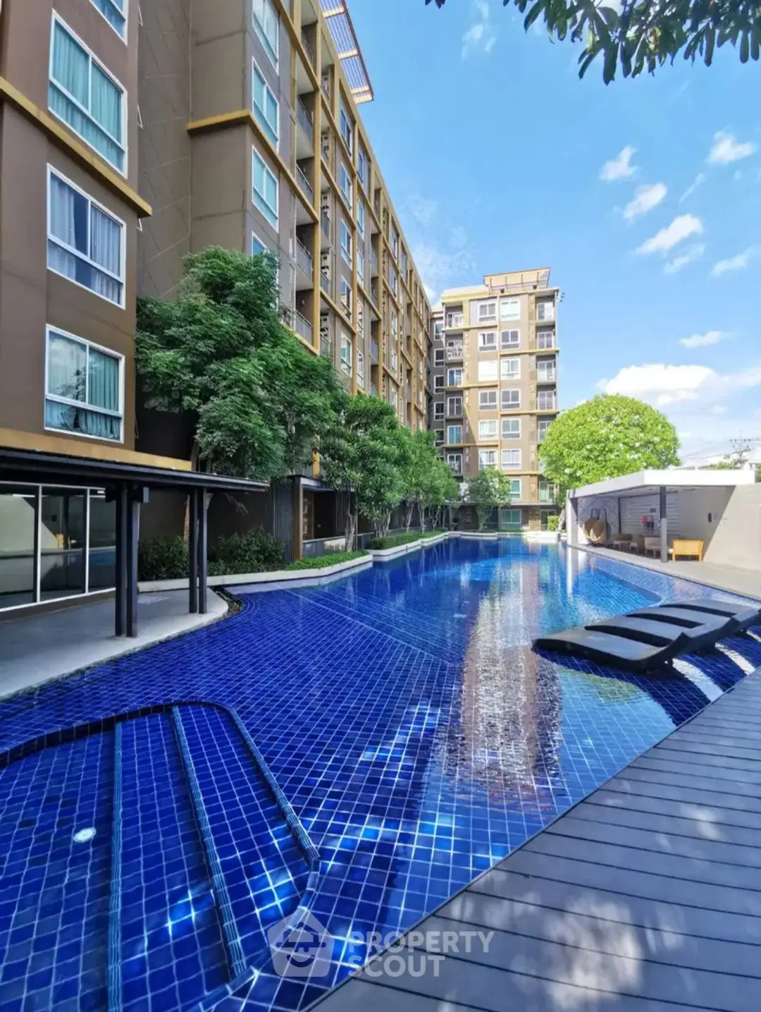 Luxurious residential complex with stunning outdoor pool and modern architecture under clear blue sky.