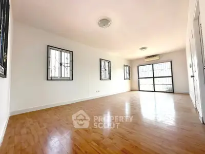 Spacious and bright living room with wooden flooring and large windows