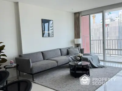 Modern living room with sleek gray sofa and balcony view in urban apartment