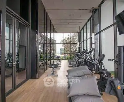 Modern gym with large windows and exercise equipment in a luxury building.