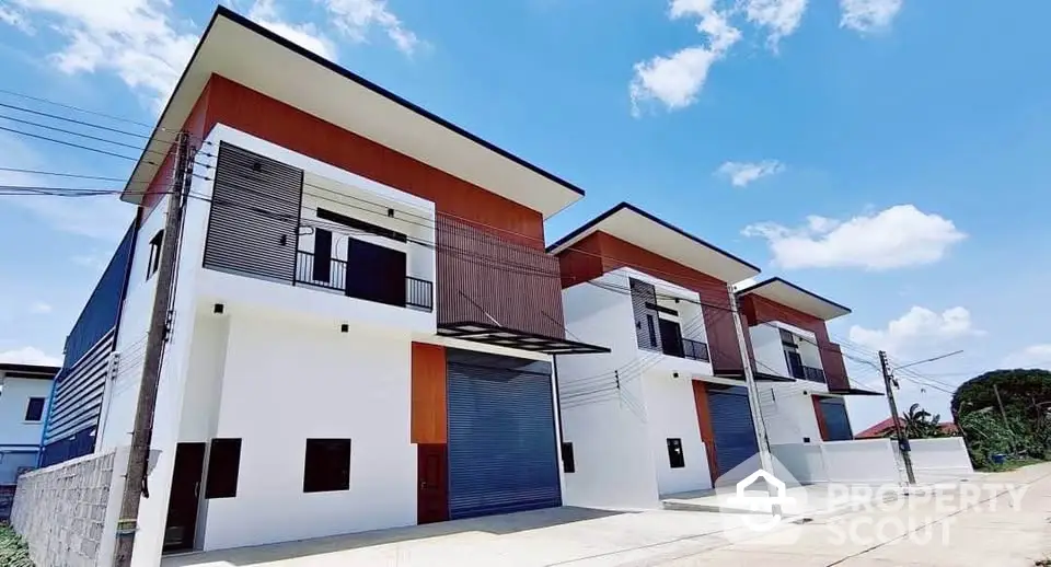 Modern townhouse exterior with sleek design and spacious balconies under clear blue sky.