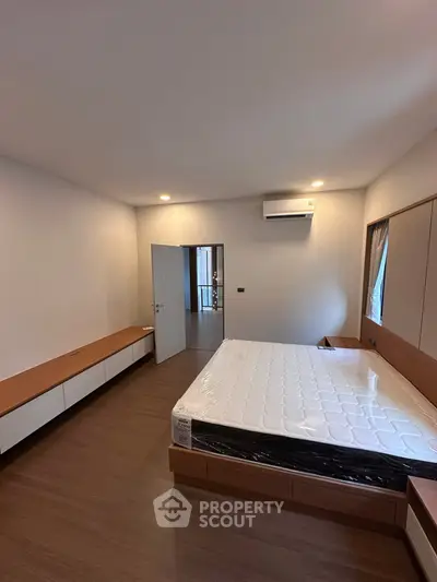 Spacious bedroom with modern design and natural light, featuring a comfortable bed and sleek wooden flooring.