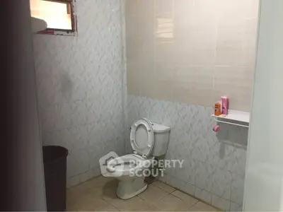 Spacious bathroom with tiled walls and modern toilet in a real estate property.