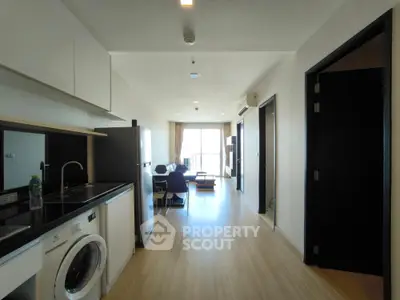 Modern open-layout apartment with kitchen and living area, featuring sleek design and natural light.