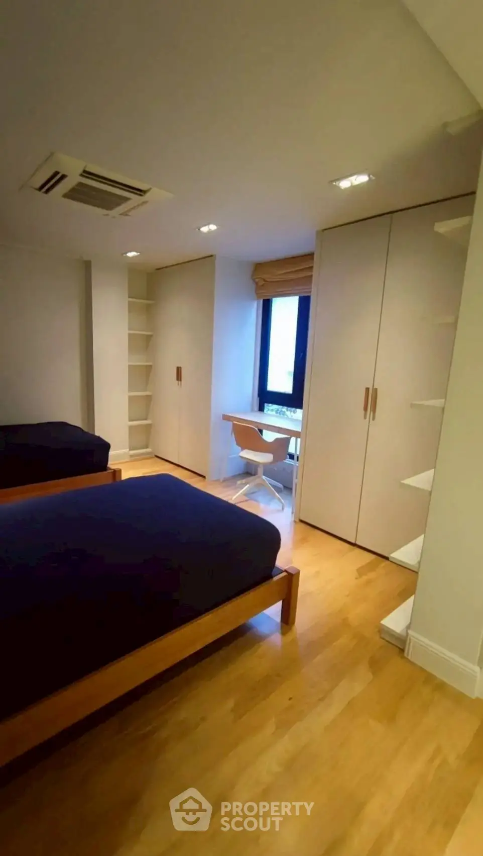 Modern bedroom with twin beds, built-in wardrobes, and a study nook.