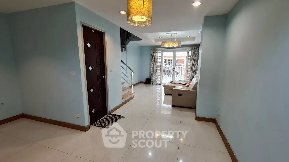 Spacious living room with modern decor and natural light, featuring a cozy sofa and elegant lighting.