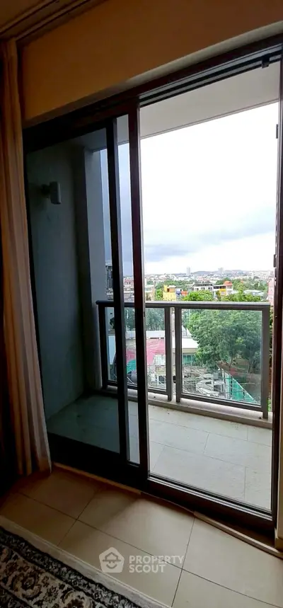 Spacious balcony with sliding glass doors offering a scenic city view, perfect for relaxation.