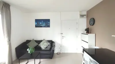 Modern living room with sleek black sofa, stylish decor, and natural light for a cozy ambiance.
