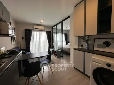 Modern open-plan apartment with stylish kitchen and cozy living area, featuring floor-to-ceiling windows and elegant decor.