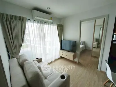 Modern living room with natural light, cozy sofa, and sleek TV setup in a stylish apartment.