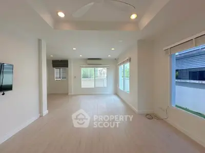 Spacious modern living room with large windows and ceiling fan