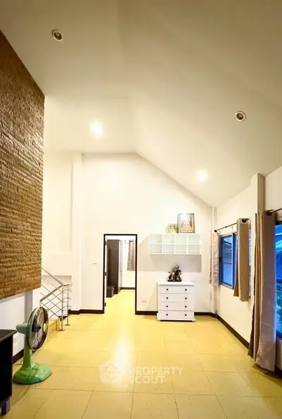 Spacious living room with high ceiling and modern decor, perfect for family gatherings.